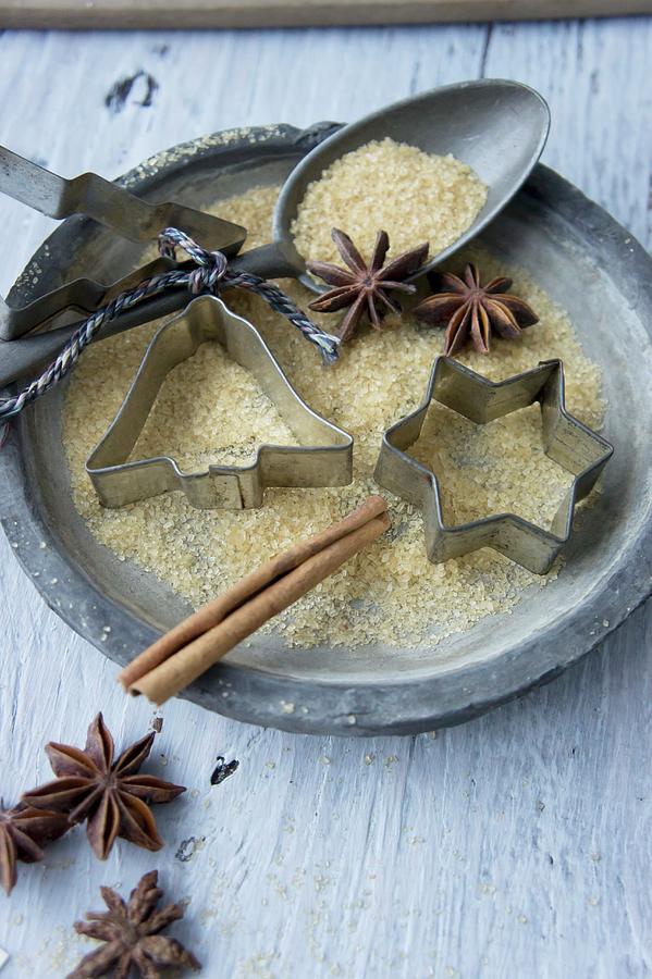 A Plate With Cookie Cutters, A Spoon, Sugar, Star Anise And A Cinnamon Stick Photograph by Martina Schindler