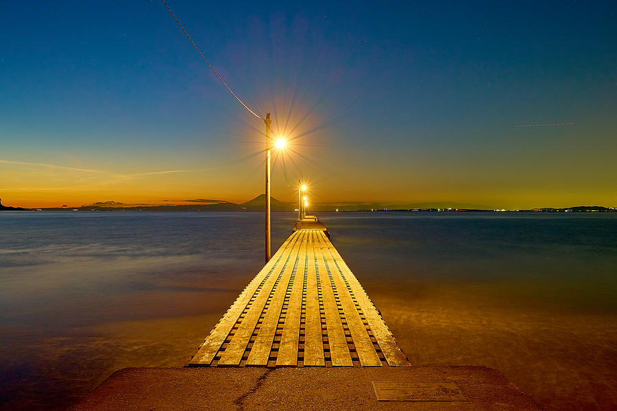 A Promenade Jutting Out Into The Sea Illuminated By Street Lamps Photograph by Kohta Agoh
