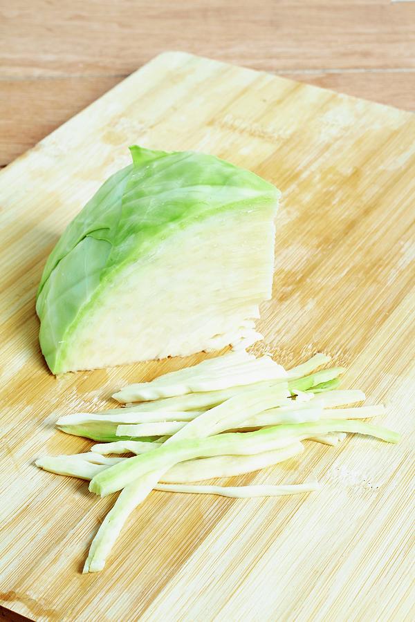 A Quarter Of A White Cabbage And Strips Of White Cabbage On A Chopping Board Photograph by Miriam Rapado