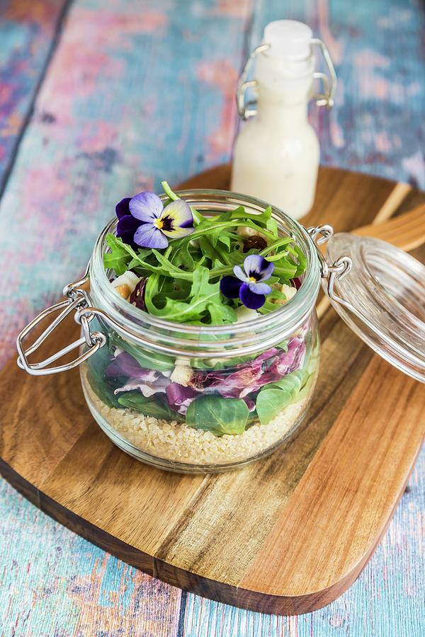 A Quinoa Salad With Lambs Lettuce, Radicchio, Rocket, Croutons, Goats Cheese And Horned Violets In A Glass Jar On A Wooden Board, With Dressing In A Glass Bottle Photograph by Sandra Rsch