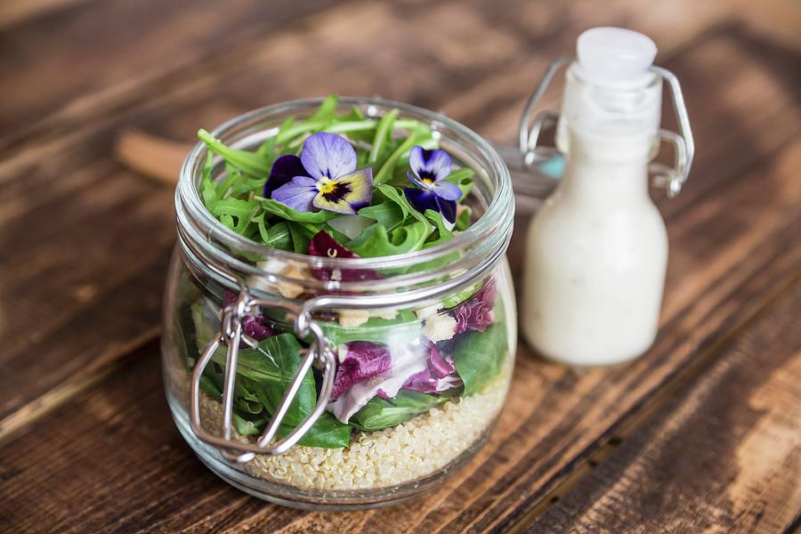 A Quinoa Salad With Lambs Lettuce, Radicchio, Rocket, Croutons, Goats Cheese And Horned Violets In A Glass Jar, With Dressing In A Glass Bottle Photograph by Sandra Rsch