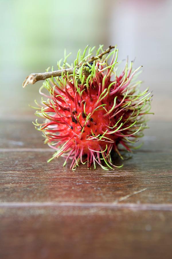 Fruit Photograph - A Rambutan On A Wooden Surface by Michael Wissing