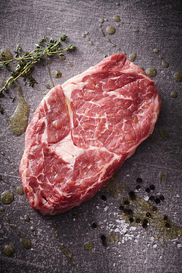 A Raw Rib-eye Steak With Thyme, Salt And Pepper Photograph by Maximilian Carlo Schmidt