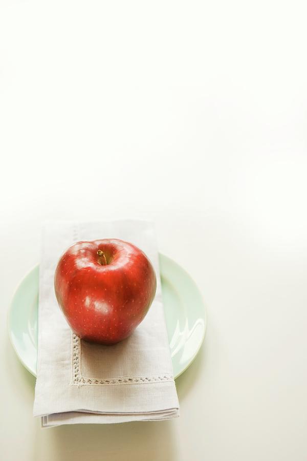 A Red Apple On A Fabric Napkin On A Plate Photograph by Colin Cooke