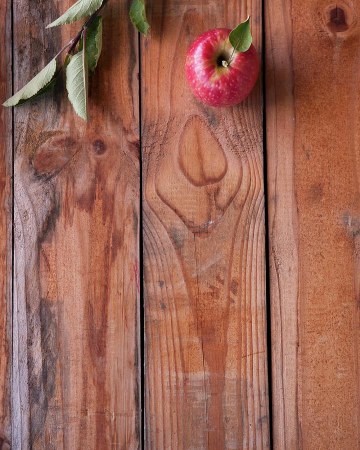 A Red Apple With A Twig On A Wooden Surface Photograph by Great Stock!
