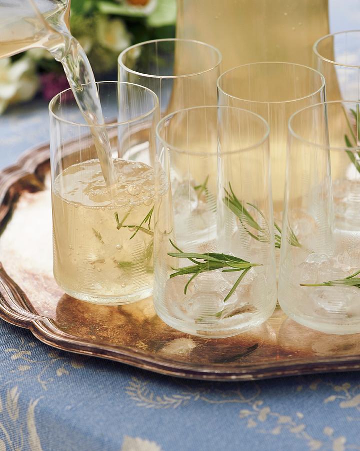 A Rosemary Drink Being Poured Into Glasses Photograph by Hannah Kompanik