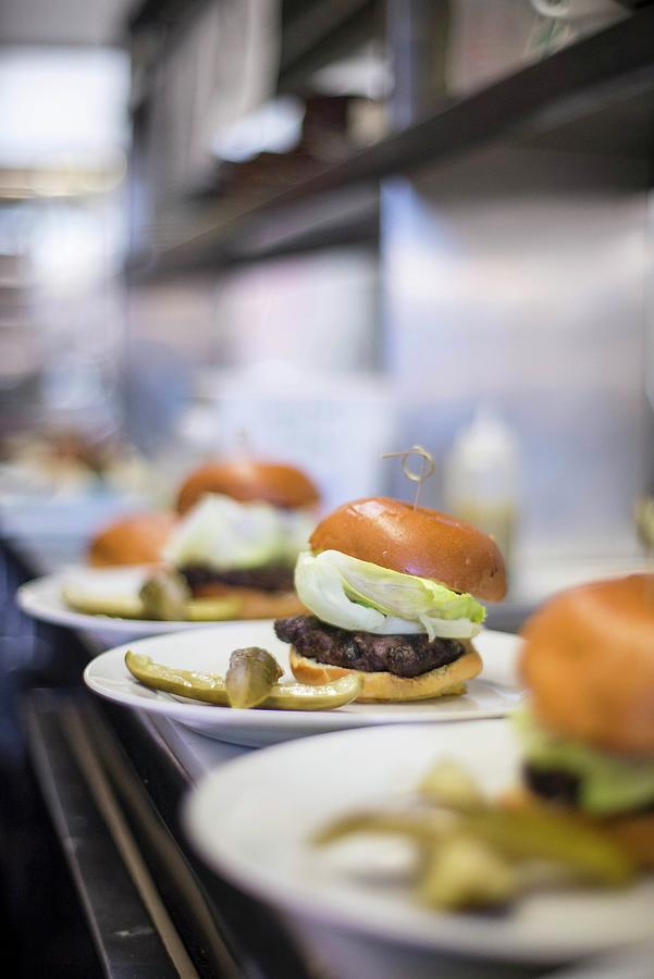 A Row Of Burgers Lined Up Ready To Serve In A Restaurant Photograph by Farrell Scott