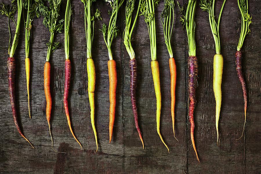 A Row Of Colourful Carrots On A Wooden Surface Photograph by Tim Atkins Photography