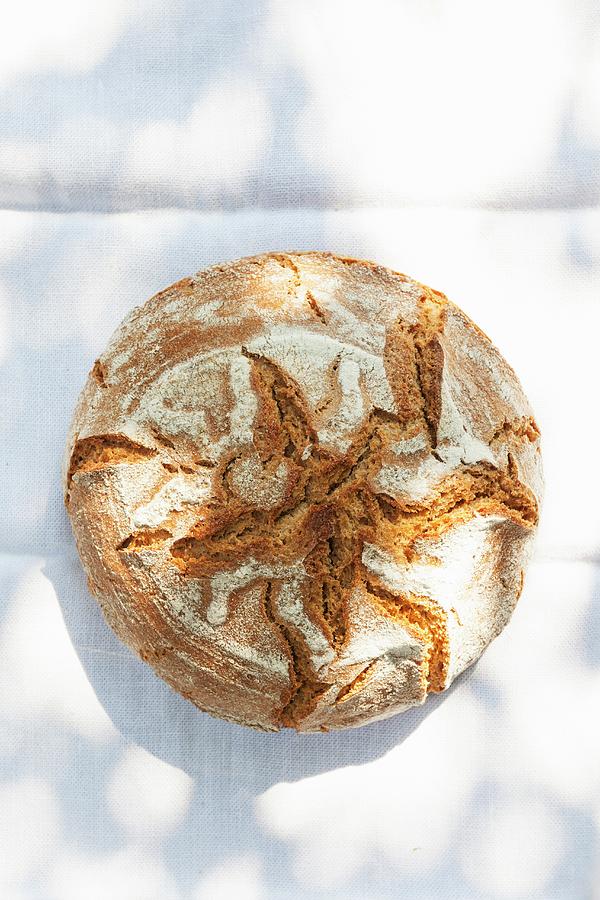 A Rustic Loaf Of Country Bread On A Sunny Table Photograph by Anneliese Kompatscher