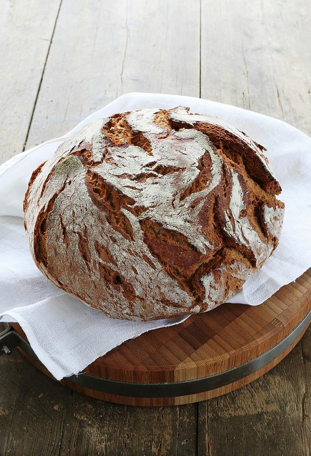 A Rustic Loaf Of Country Bread On A Wooden Board With A White Cloth Photograph by Regina Hippel