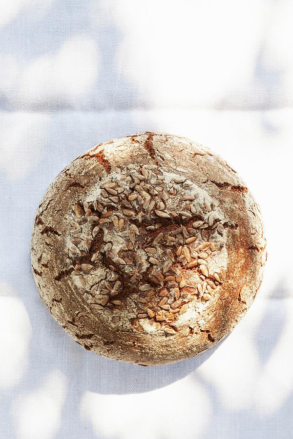 A Rustic Loaf Of Sunflower Seed Bread On A Sunny Table Photograph by Anneliese Kompatscher
