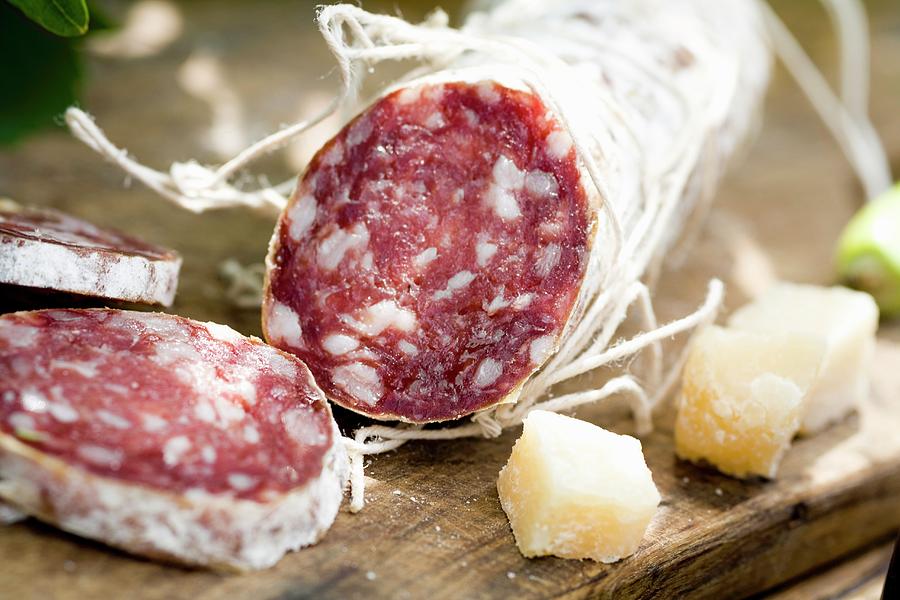 A Salami, Partly Sliced, And Cubes Of Parmesan Photograph by Imagerie
