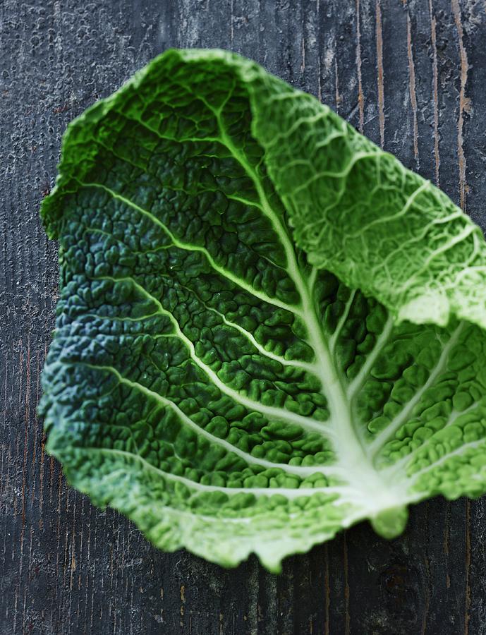 A Savoy Cabbage Leaf On A Weathered Wooden Surface Photograph by Lars Ranek