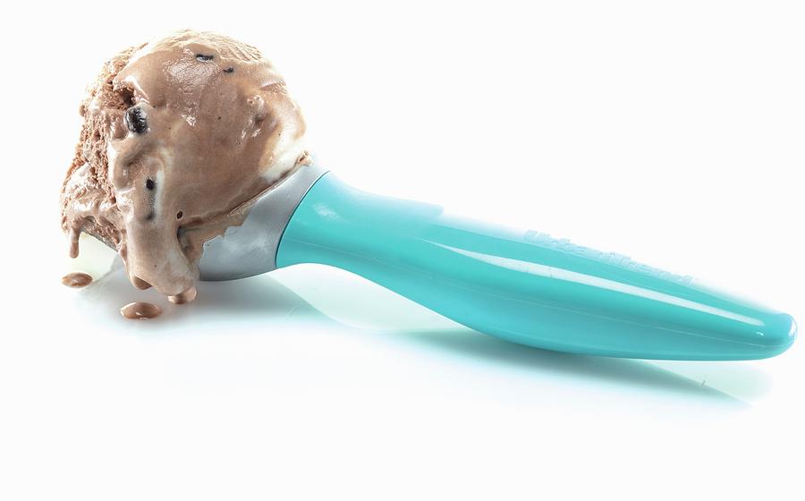 A Scoop Of Chocolate Ice Cream In A Blue Ice Cream Scoop Against A White Background Photograph by Cindy Haigwood