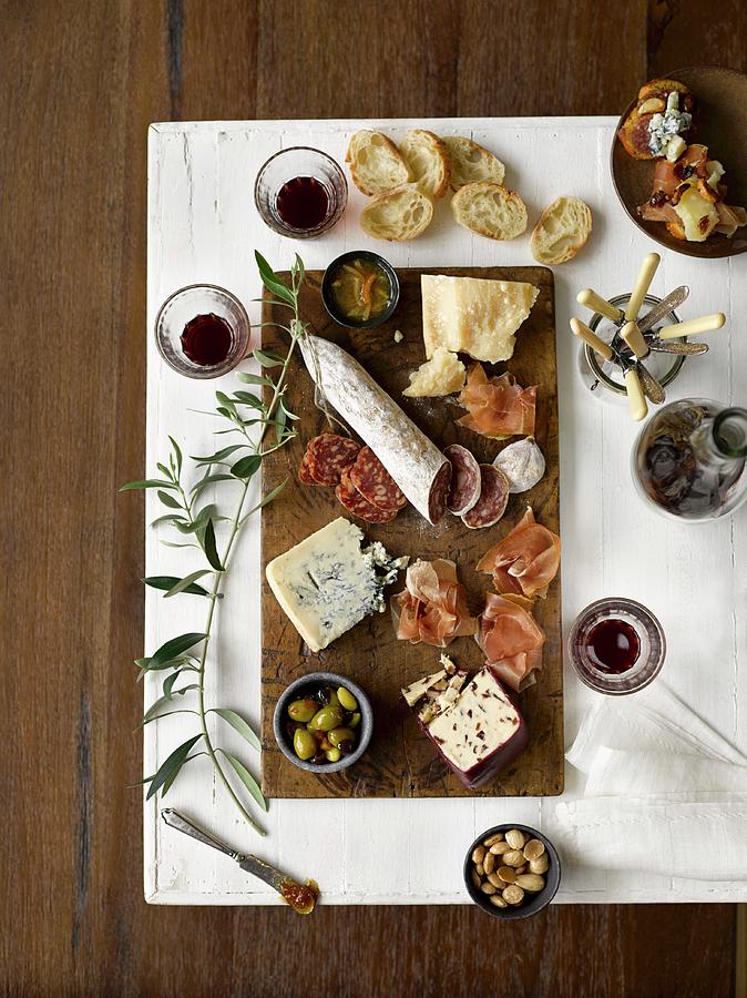 A Selection Of Cold Cuts With Cheese, Prosciutto, Olives, Bread, Almonds, Jam And Red Wine Photograph by Laurie Proffitt