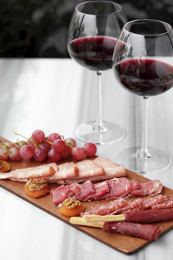 A Selection Of Cold Meats With Grapes And Two Glasses Of Red Wine Photograph by Ernalbant, Emel
