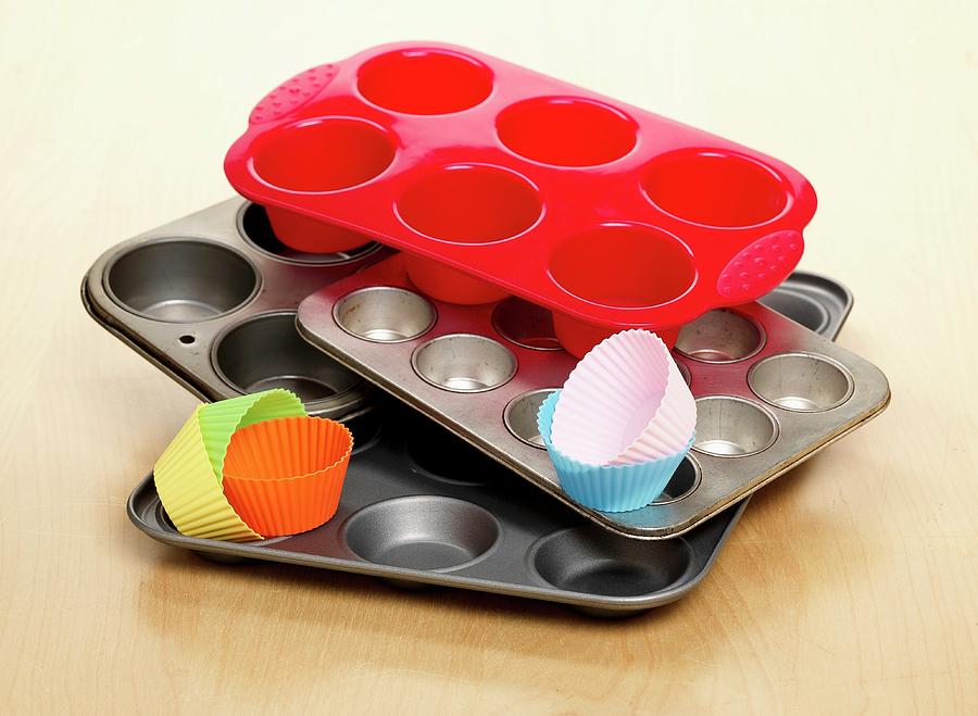 A Selection Of Different Types Of Baking Trays And Cases For Making Cupcakes Shown On A Wooden Surface Photograph by Stuart Macgregor