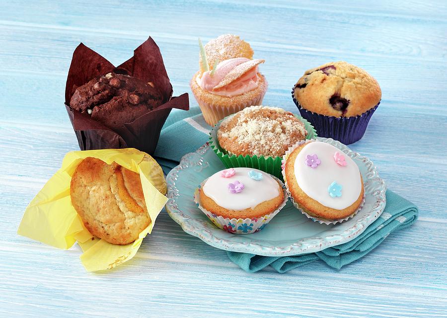 A Selection Of Various Cupcakes And Muffins On A Blue Surface, Blue Plate And Napkin Photograph by Stuart Macgregor