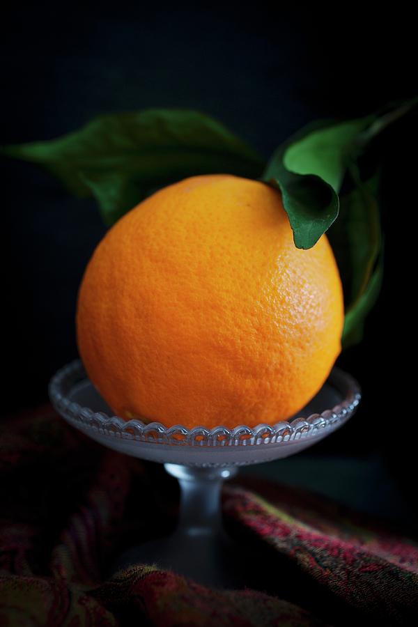 A Seville Orange With Leaves In A Glass Bowl Photograph by Victoria Harley