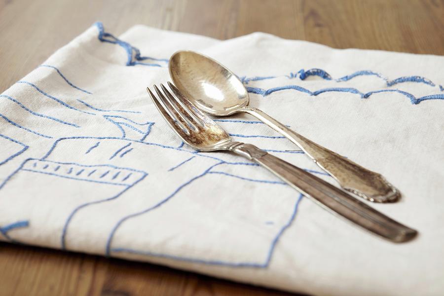 A Silver Fork And A Silver Spoon On A Tea Towel Photograph by Lewis-harrison, Debby