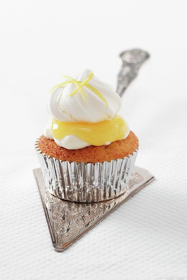 A Single Lemon Meringue Cupcake With Lemon Curd In A Silver Case Sitting On A Silver Cake Slice Photograph by Stuart Macgregor