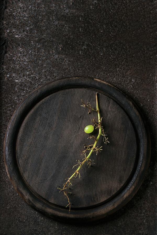 A Single White Grape On A Stalk On A Wooden Plate seen From Above Photograph by Natasha Breen