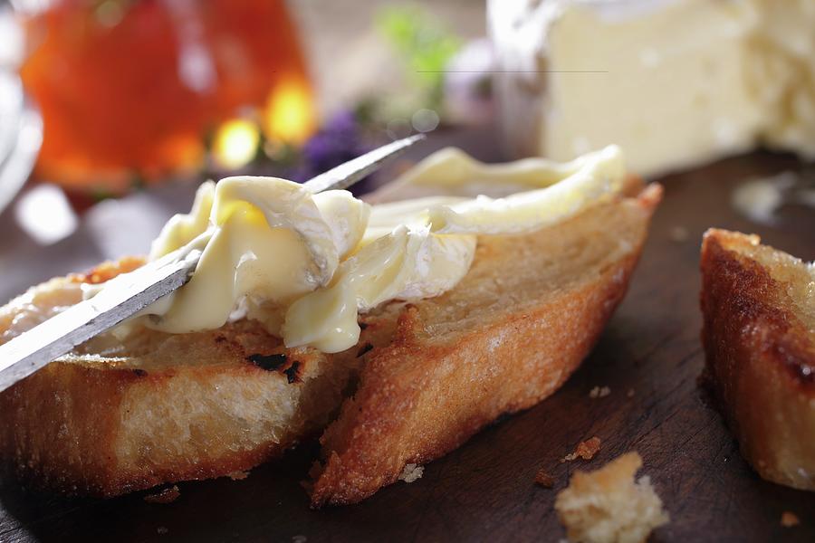 A Slice Of Baguette Being Spread With Camembert Photograph by Frank Weymann