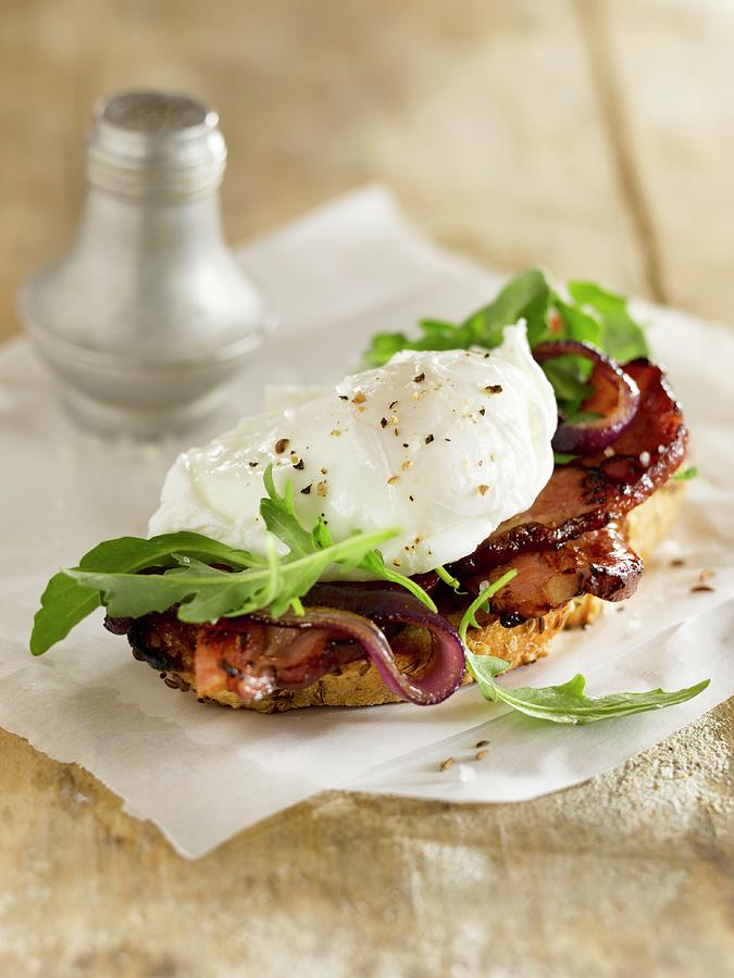A Slice Of Bread Topped With A Poached Egg, Bacon And Rocket Photograph by Laurie Proffitt