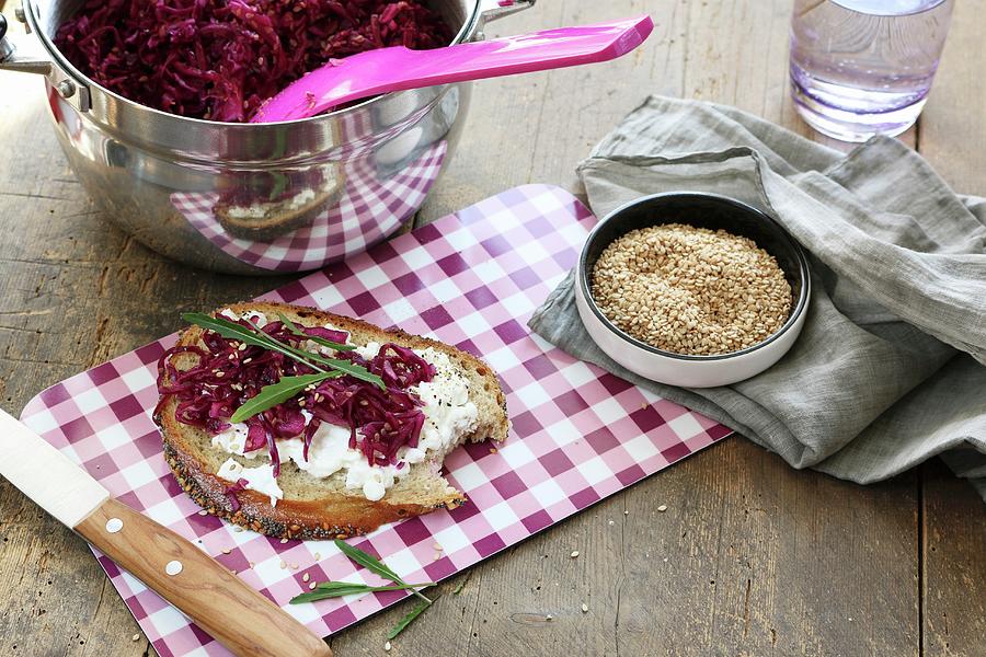 A Slice Of Bread Topped With Cream Cheese, Red Cabbage, Rocket And Sesame Seeds On A Checked Breakfast Board Photograph by Regina Hippel
