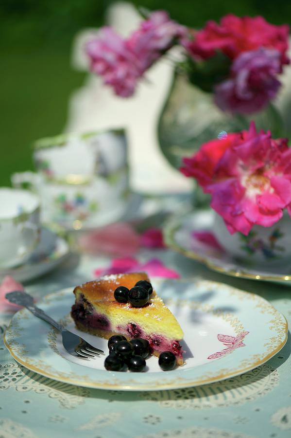 Fruit Photograph - A Slice Of Cheesecake With Blackcurrants On A Table In The Garden by Heinze, Winfried