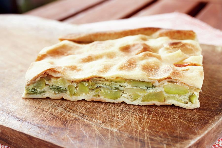 A Slice Of Courgette, Egg And Quark Pie With Flaky Pastry On A Wooden Chopping Board Photograph by Luzzitelli Danieli & Associati S.a.s.