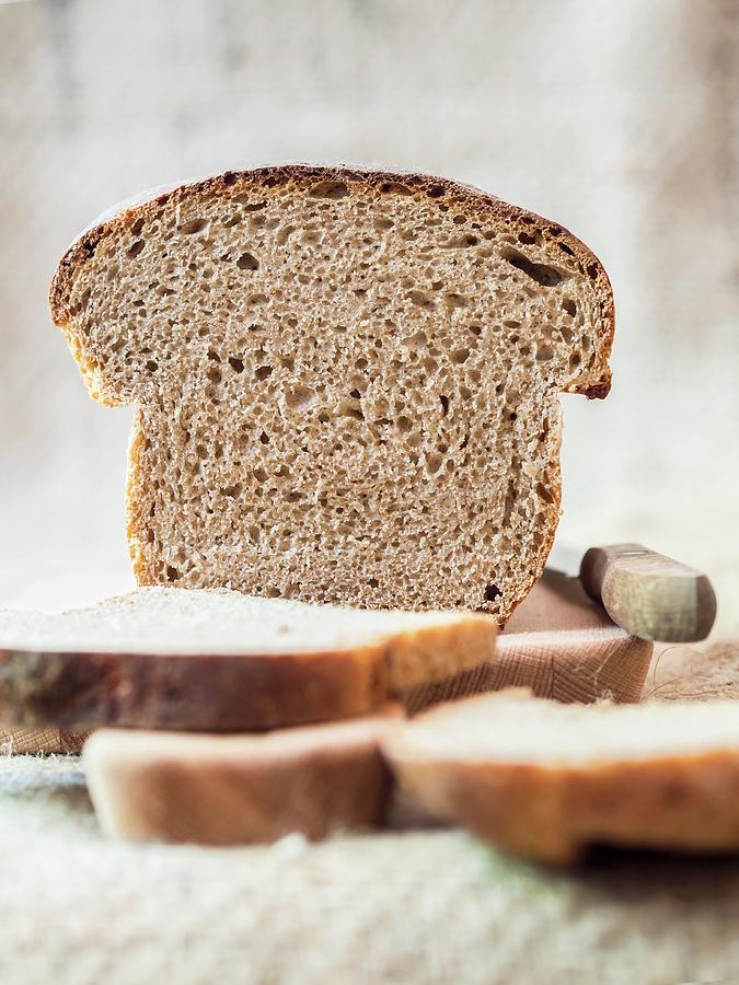 A Slice Of Homemade Sourdough Bread On A Chopping Board Photograph by Magdalena Paluchowska