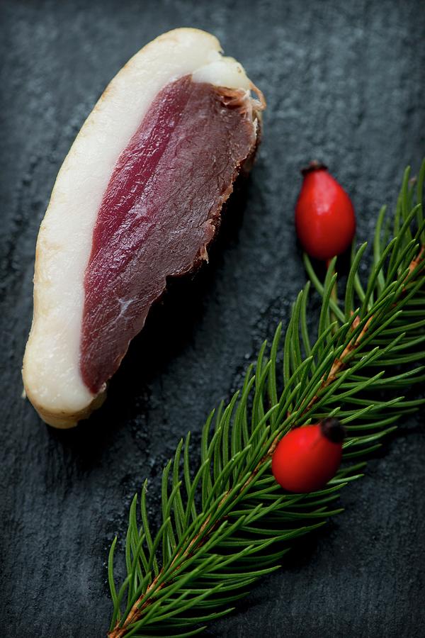A Slice Of Smoked, Marinated Duck Breast With A Sprig Of Spruce And Rose Hips On A Slate Platter Photograph by Jamie Watson