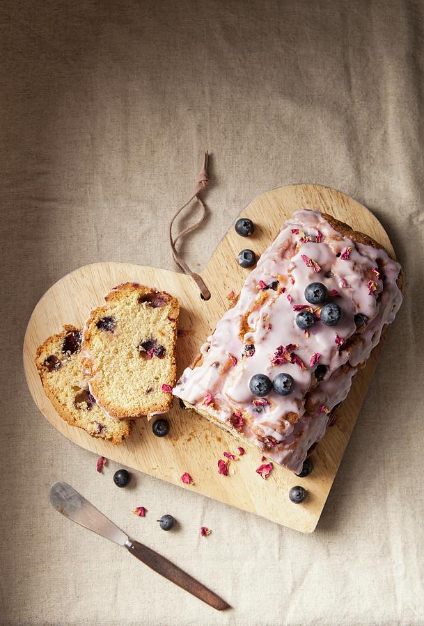 A Sliced Blueberry Loaf Cake With Icing And Dried Rose Petals Photograph by Stacy Grant