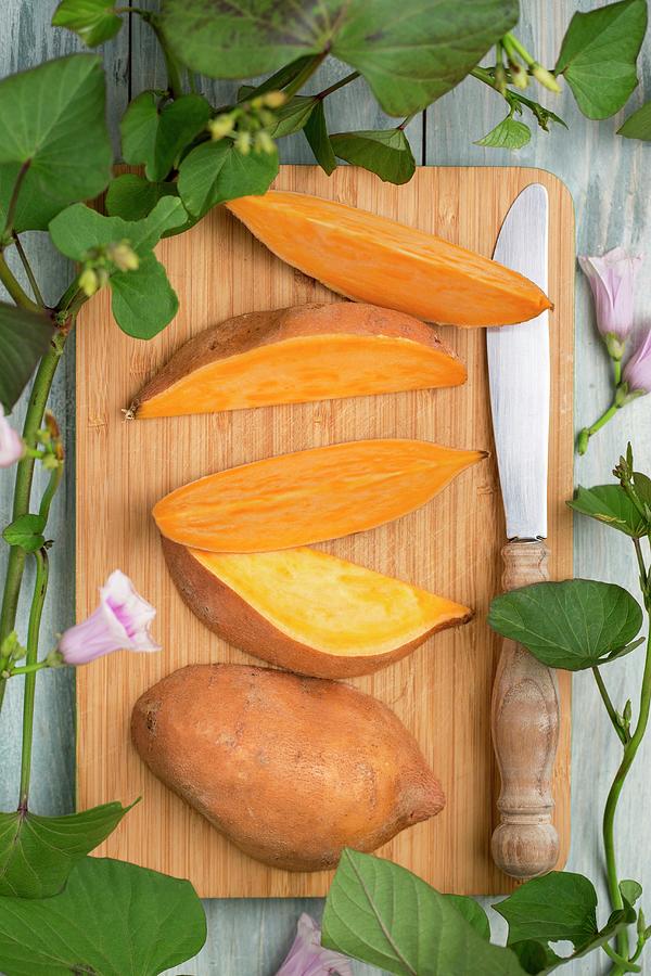 A Sliced Sweet Potato With Sweet Potato Leaves And Flowers Photograph by Sandra Krimshandl-tauscher