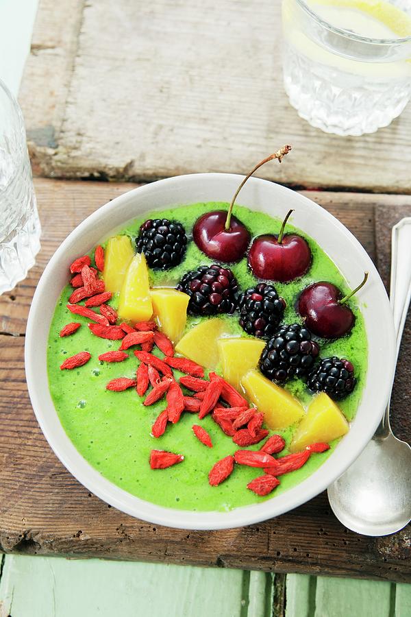 A Smoothie Bowl With Spinach, Kiwi And Apple Garnish With Goji Berries, Peaches, Cherries And Blackberries Photograph by Victoria Firmston