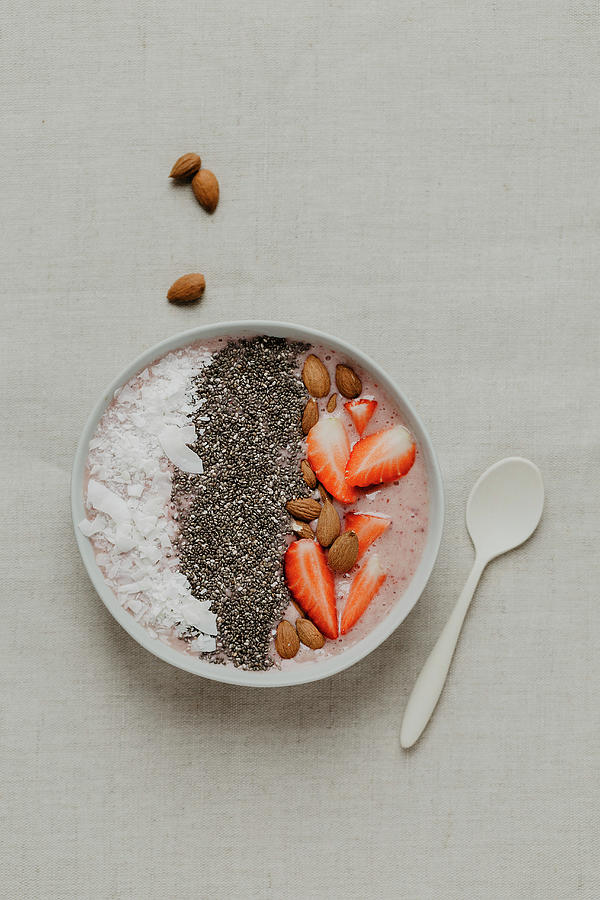 A Smoothie Bowl With Strawberries, Chia, Almonds And Coconut Flakes Photograph by Valeria Aksakova