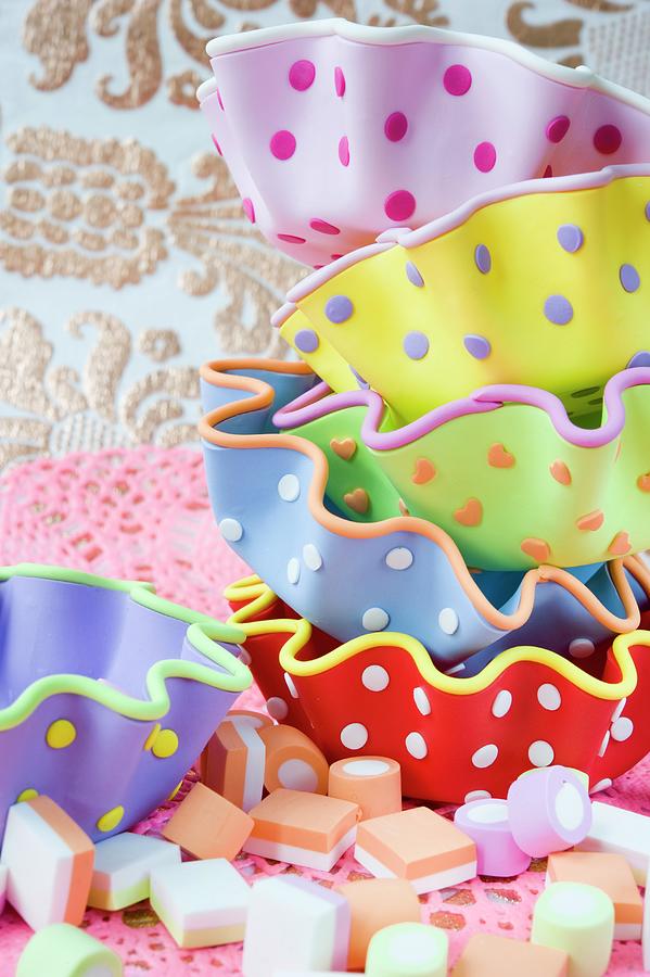 A Stack Of Colourful Spotted Cupcake Moulds And Some Sweets Photograph by Burgess, Jasmine