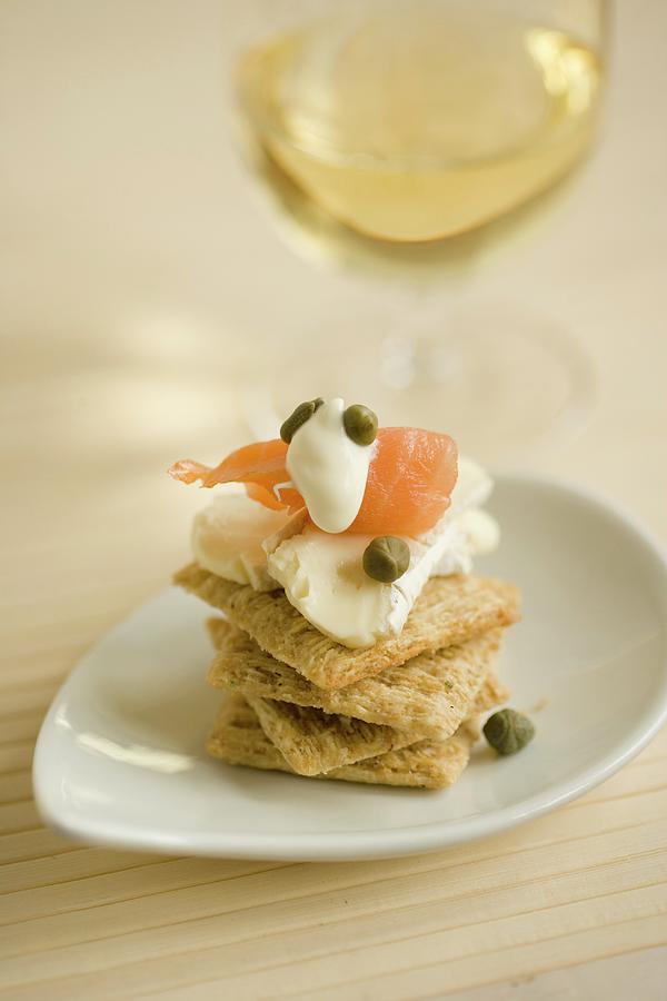 A Stack Of Crackers Topped With Soft Cheese, Salmon And Capers Served With White Wine Photograph by Colin Cooke
