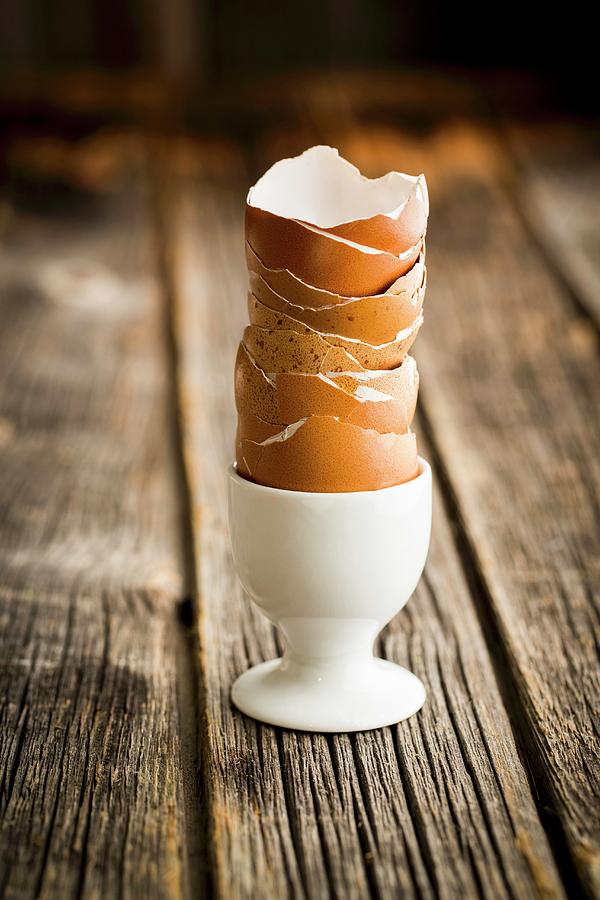 A Stack Of Empty Egg Shells In An Egg Cup Photograph by Sandra Krimshandl-tauscher