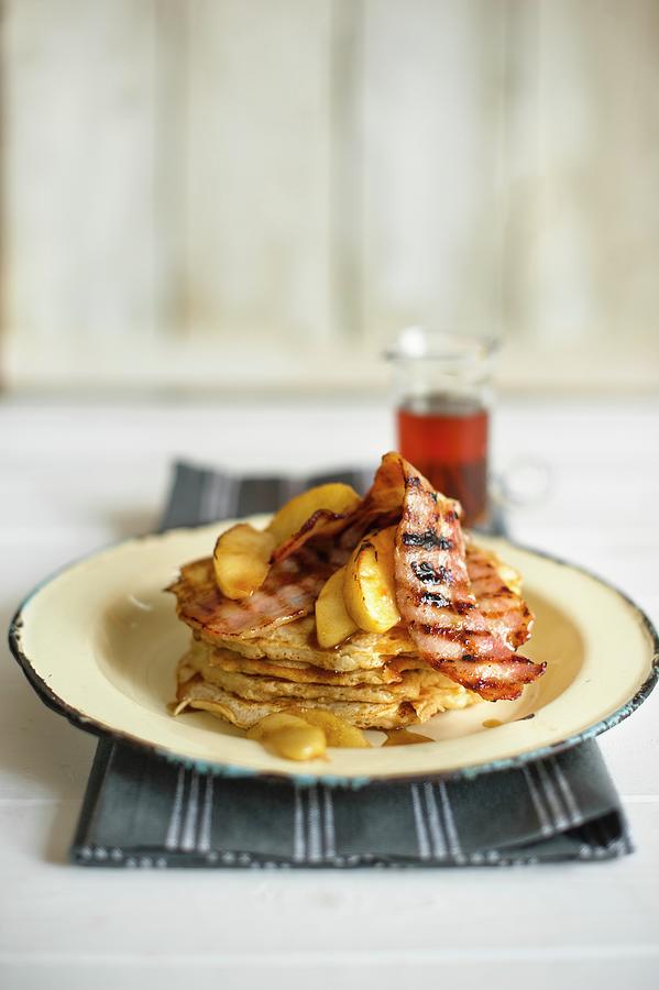 A Stack Of Pancakes On A Plate With Grilled Bacon And Apple With Maple Syrup In The Background Photograph by Magdalena Hendey