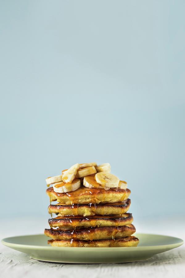 A Stack Of Pancakes Topped With Banana Slices And With Dripping Maple Syrup Photograph by Malgorzata Laniak
