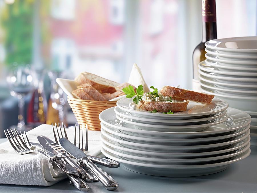 A Stack Of Plates, Cutlery And Baguette With Cream Cheese Photograph by Ludger Rose