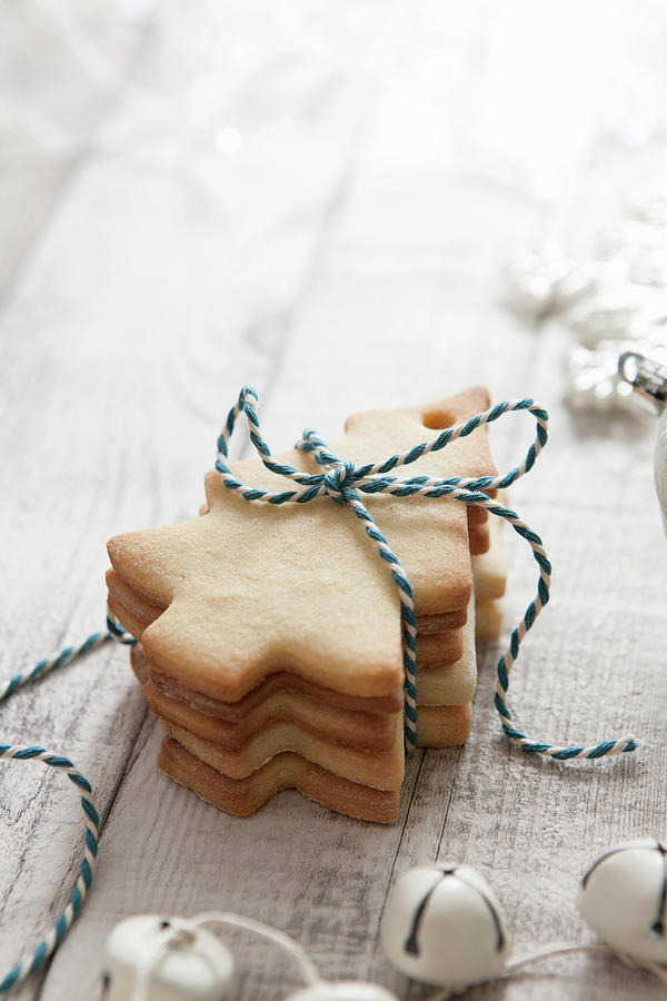 A Stack Of Tree Shaped Biscuits Tied With Blue And White Bakers Twine In A White Christmas Setting Photograph by Stacy Grant