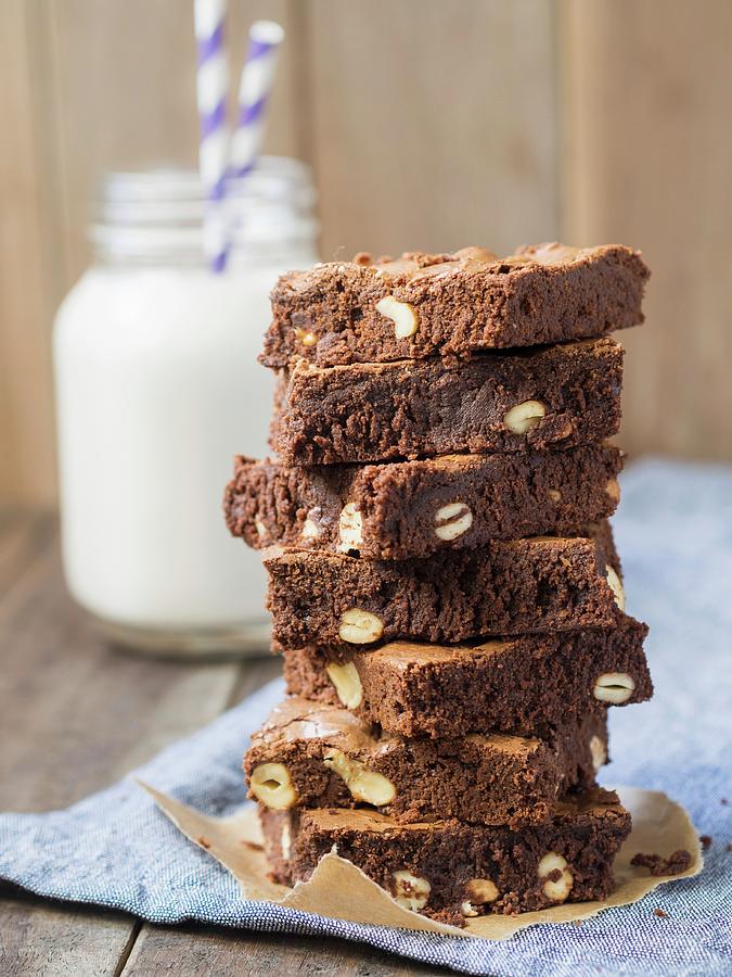 Candy Photograph - A Stack Of Wholegrain Organic Brownies With Cashew Nuts And A Glass Of Milk In The Background by Magdalena Paluchowska