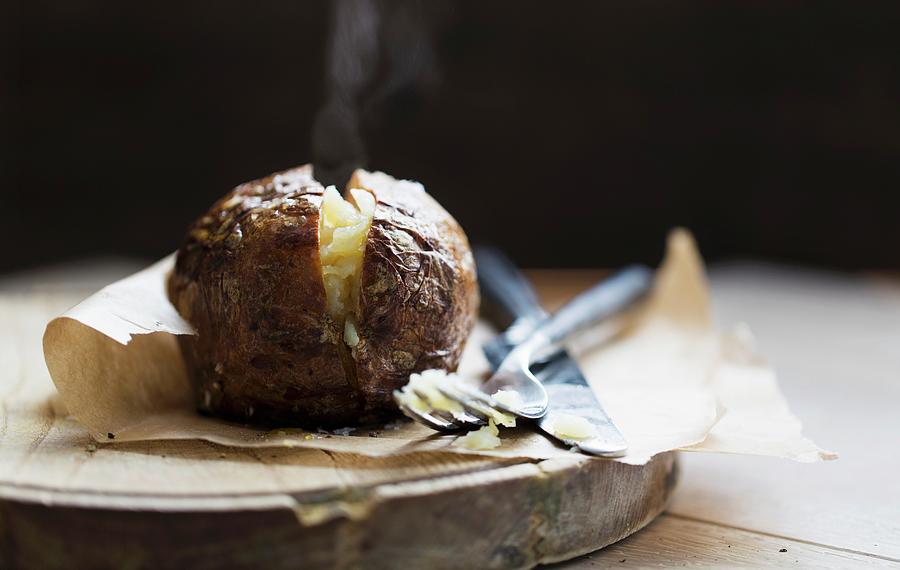 A Steaming Baked Potato On A Piece Of Baking Paper Photograph by Cath Lowe