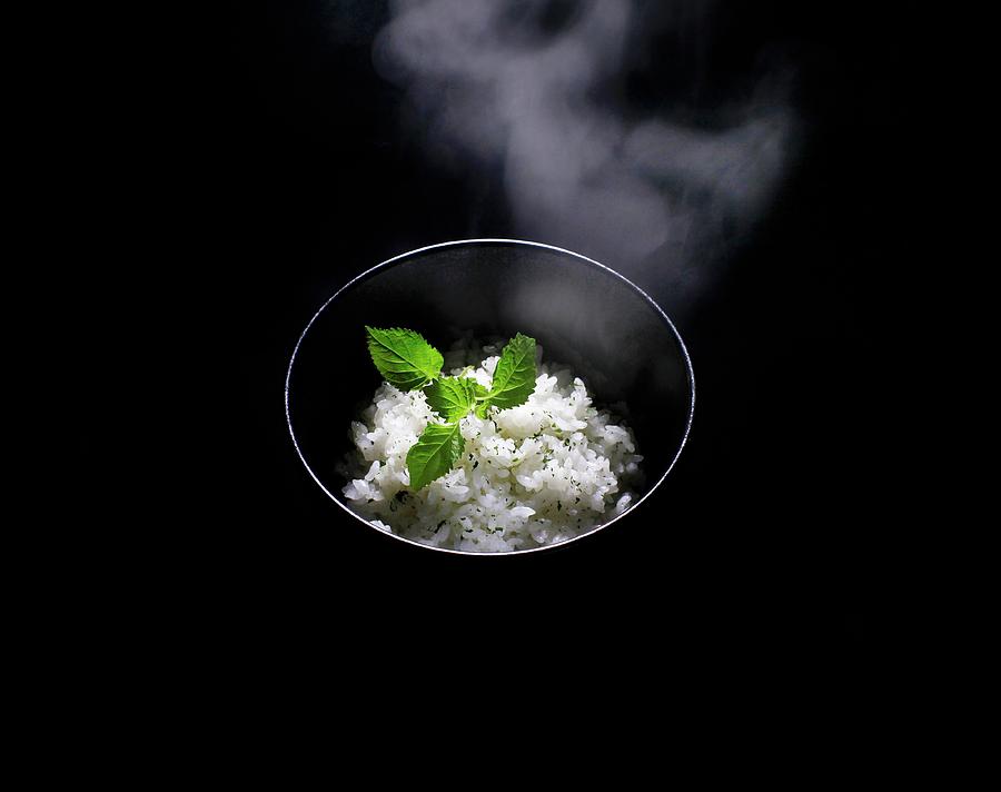 A Steaming Bowl Of Japanese Rice With A Small Shiso Leaf; Black Background Photograph by Mueller, Adrian