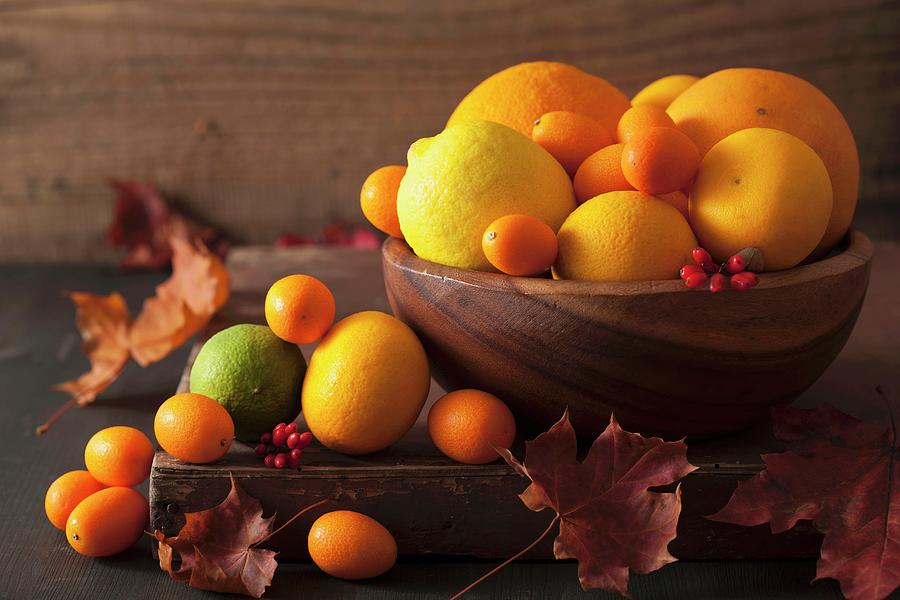 A Still Life Featuring Citrus Fruits And Autumn Leaves Photograph by Olga Miltsova
