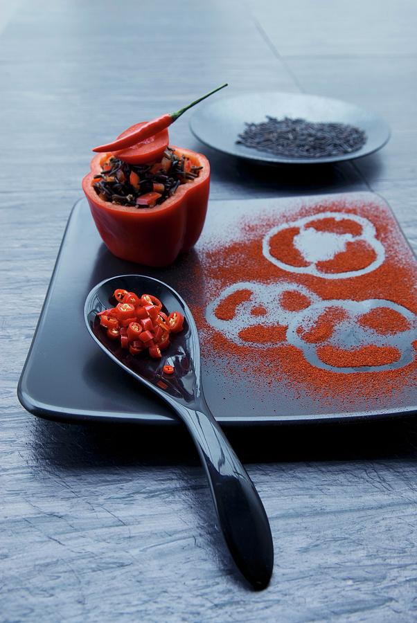 A Stuffed Pepper Filled With Wild Rice, Chilli And Tomatoes With A Spoonful Of Chilli Rings And A Black Plate With Paper Prints In Paprika Powder Photograph by Matteo Manduzio