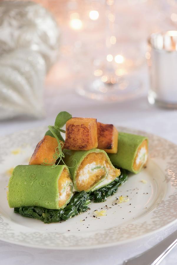A Stuffed Pumpkin Pasta Roll On A Bed Of Cooked Spinach For Christmas Photograph by Winfried Heinze